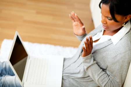 Top view portrait of a confused and surprised young woman reading a message on laptop screen while sitting on the floor at home indoorの写真素材