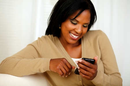 Portrait of a lovely young woman sending a message by her cellphone at soft colors compositionの写真素材