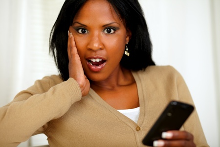 Portrait of a surprised woman looking to you while using her cellphoneの写真素材