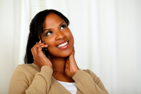 Portrait of a charming girl looking up and conversing on mobile at home indoorの写真素材