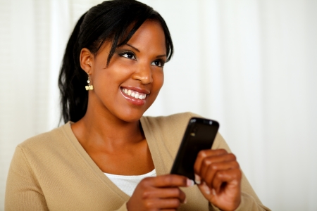 Portrait of a smiling female sending a message by the cellphone at soft colors compositionの写真素材