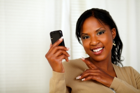 Portrait of a charming woman reading a message on cellphone while looking at youの写真素材