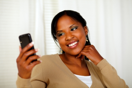 Portrait of a friendly black woman sending a text message by the cellphoneの写真素材