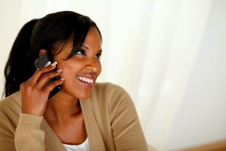 Top view portrait of an afro-American young woman conversing on cellphone while is looking upの写真素材