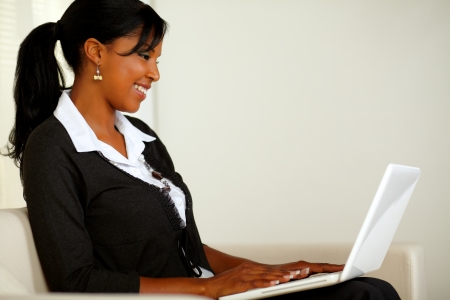 Portrait of a beautiful business black woman reading on laptop while sitting on couchの写真素材