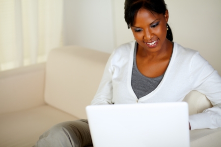 Portrait of a charming young woman working on laptop while sitting on sofaの写真素材