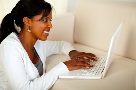 Portrait of a smiling black lady working on laptop at home indoorの写真素材