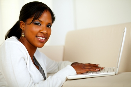 Portrait of a stylish girl looking at you while working on laptop at home indoor. With copyspaceの写真素材