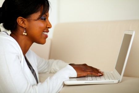 Portrait of a smiling afro-American woman using a laptop at home indoorの写真素材