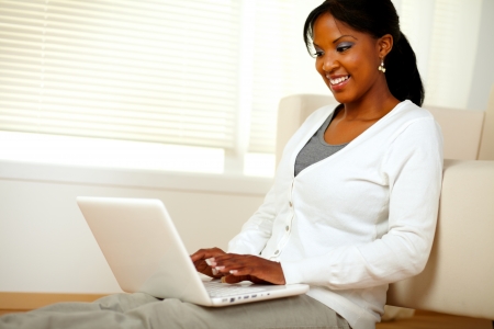 Portrait of a charming young woman working on laptop while sitting on the floor. With copyspaceの写真素材
