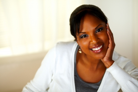 Portrait of a charming young woman smiling and looking at you while sitting on couch. With Copyspaceの写真素材