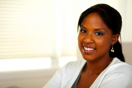 Portrait of a relaxed afro-American young female smiling at you at home. With copyspaceの写真素材