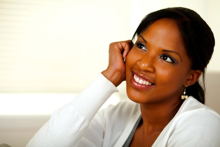 Portrait of a pensive young black woman looking up at home indoor. With copyspaceの写真素材