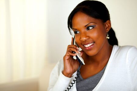 Portrait of an afro-American woman conversing on phone at soft colors composition. With copyspaceの写真素材
