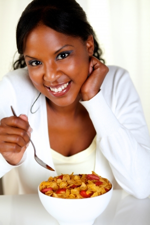 Portrait of a relaxed woman looking at you and having breakfast at soft colors compositionの写真素材