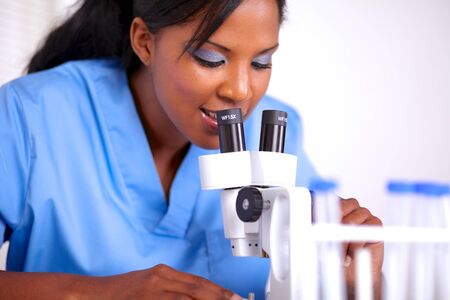 Young scientific woman using a microscope at laboratory - portraitの写真素材