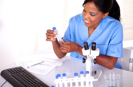 Beautiful scientific female looking to test tube at laboratory in blue uniformの写真素材