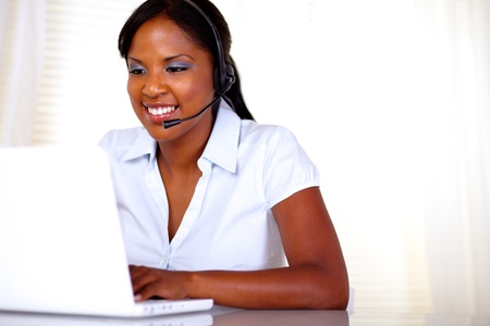 Attractive young call center operator working on laptop and speaking on microphone - copyspaceの写真素材
