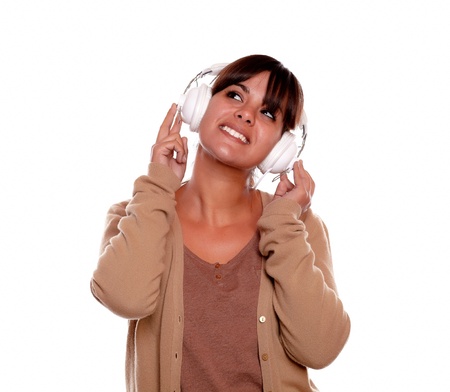 Portrait of a smiling young woman looking up with headphones against white background