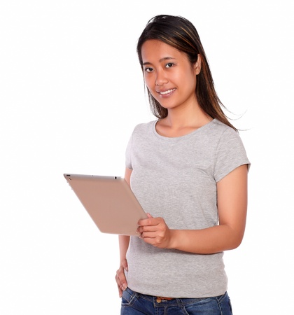 Portrait of a smiling asiatic young woman using her tablet pc against white backgroundの写真素材