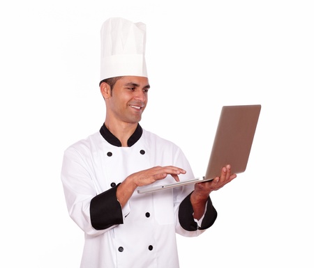 Portrait of a handsome male in chef uniform working on computer on isolated backgroundの写真素材