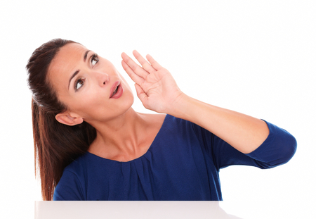 Cute lady in blue shirt looking up while speaking in white background - copyspace