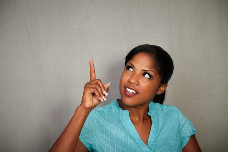 African girl with straight hair pointing up while looking away - copy spaceの写真素材