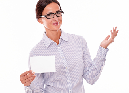 Smiling brunette businesswoman with glasses, wearing her long hair tied back, and a button down shirt, gesturing, holding a blank copy space in one hand on a white backgroundの写真素材