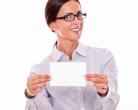 Happy brunette businesswoman with glasses, wearing her long hair tied back, and a button down shirt, looking excited, holding a blank copy space with both hands in front of herの写真素材