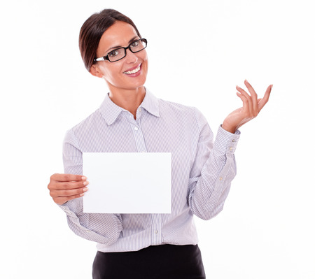 Excited brunette businesswoman with glasses, wearing her long hair tied back, and a button down shirt, holding a blank signboard in one hand, gesturing with the other handの写真素材