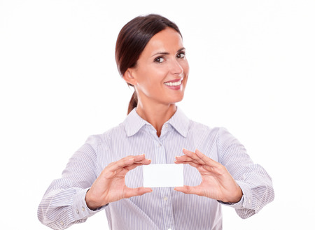 Businesswoman showing a happy toothy smile, looking at the camera with straight brown hair that is tied up at the back, wearing a button down shirt, holding up a blank visit cardの写真素材