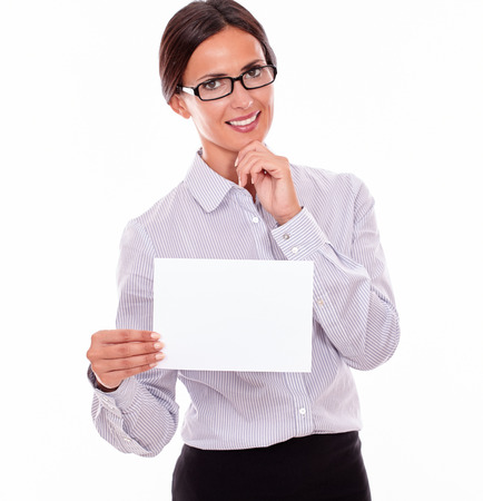 Excited brunette businesswoman with glasses, wearing her long hair tied back, and a button down shirt, holding a blank signboard in one hand, and pointing at it with the other handの写真素材