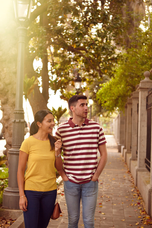 Young couple strolling leisurely down a road sightseeing, smiling happily while dressed casually in jeans and t-shirtsの写真素材