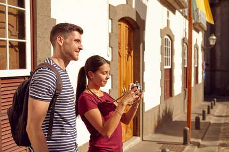 Young tourist couple on vacation with a backpack taking a picture in a narrow street while dressed in casual clothesの写真素材