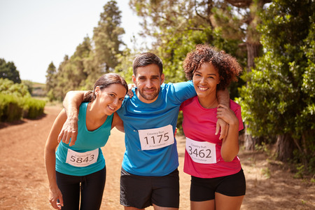 Three happy runners at the end of a cross country marathon with trees behind them wearing casual running clothes in the late morningの写真素材
