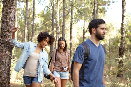 Three friends walking leisurely through a pine tree plantation in the late afternoon sunshine while wearing casual clothingの写真素材