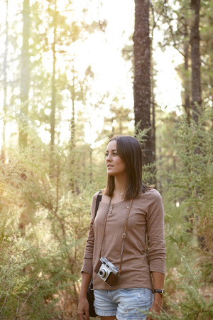 Young girl looking wonderingly around her and listening in the forest of pine trees while wearing casual clothingの写真素材