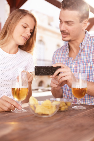 Handsome guy explaining something about his phone to a beautiful girl while he is looking at her admiringlyの写真素材