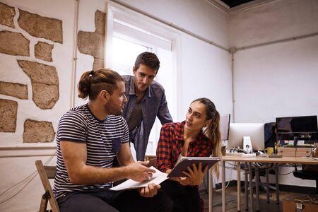 Team of three young sales representatives in a strategic meeting looking at one of the guys explaining a new strategyの写真素材