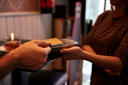 A gold credit card held out to a credit card machine held out by a femaleの写真素材