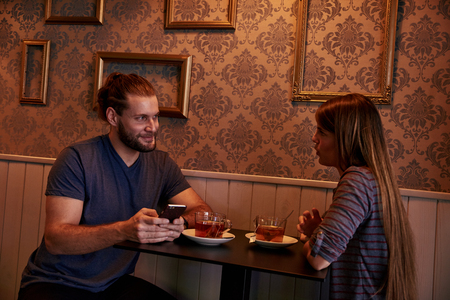 Chatting young couple chatting in a pub while looking at each other with big smiles as they sit at a small tableの写真素材