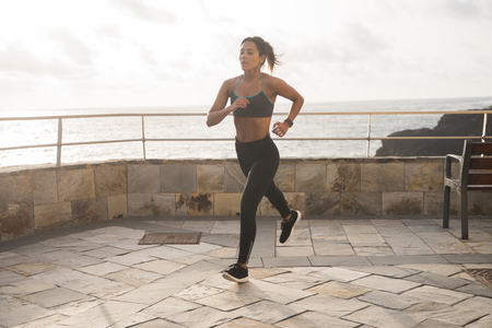 A pretty brunette running on the promenade in tights and a tank top with her hair tied backの写真素材