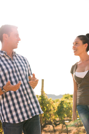 Man in checkered shirt talking to a woman in casual clothing outside in the winelands on a sunny day
