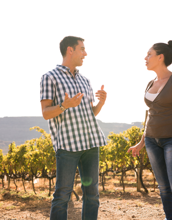 Couple at the vineyard talking to each other in casual wear on a bright sunny dayの写真素材