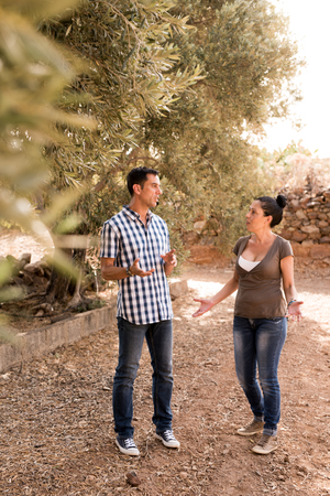 Man and woman having a converstation outside on a sunny day wearing casual jeans and shirtsの写真素材