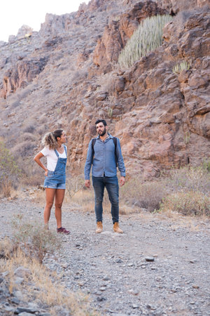 Man and woman standing and talking on a mountain path, the path is rocky and grassyの写真素材