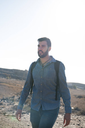 Man walking in the desert along a trail as he looks up at the horizon