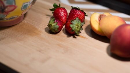 Wooden board with red and fresh strawberries and peaches for breakfast. Idea of a fresh and nutritious breakfast. Healthy and healthy lifestyle. Season fruitsの写真素材
