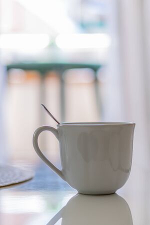 Cup with spoon on a white table with the street in the backgroundの写真素材