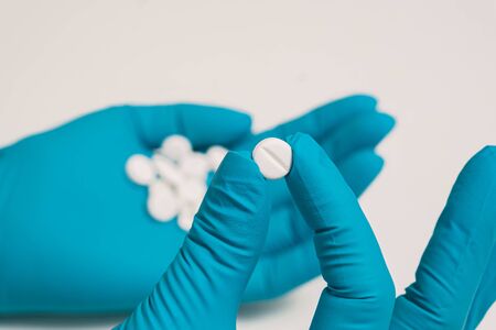 The doctor's blue-gloved hand holds the medicine. A nurse passes a pill. Taking pills. Helping a...